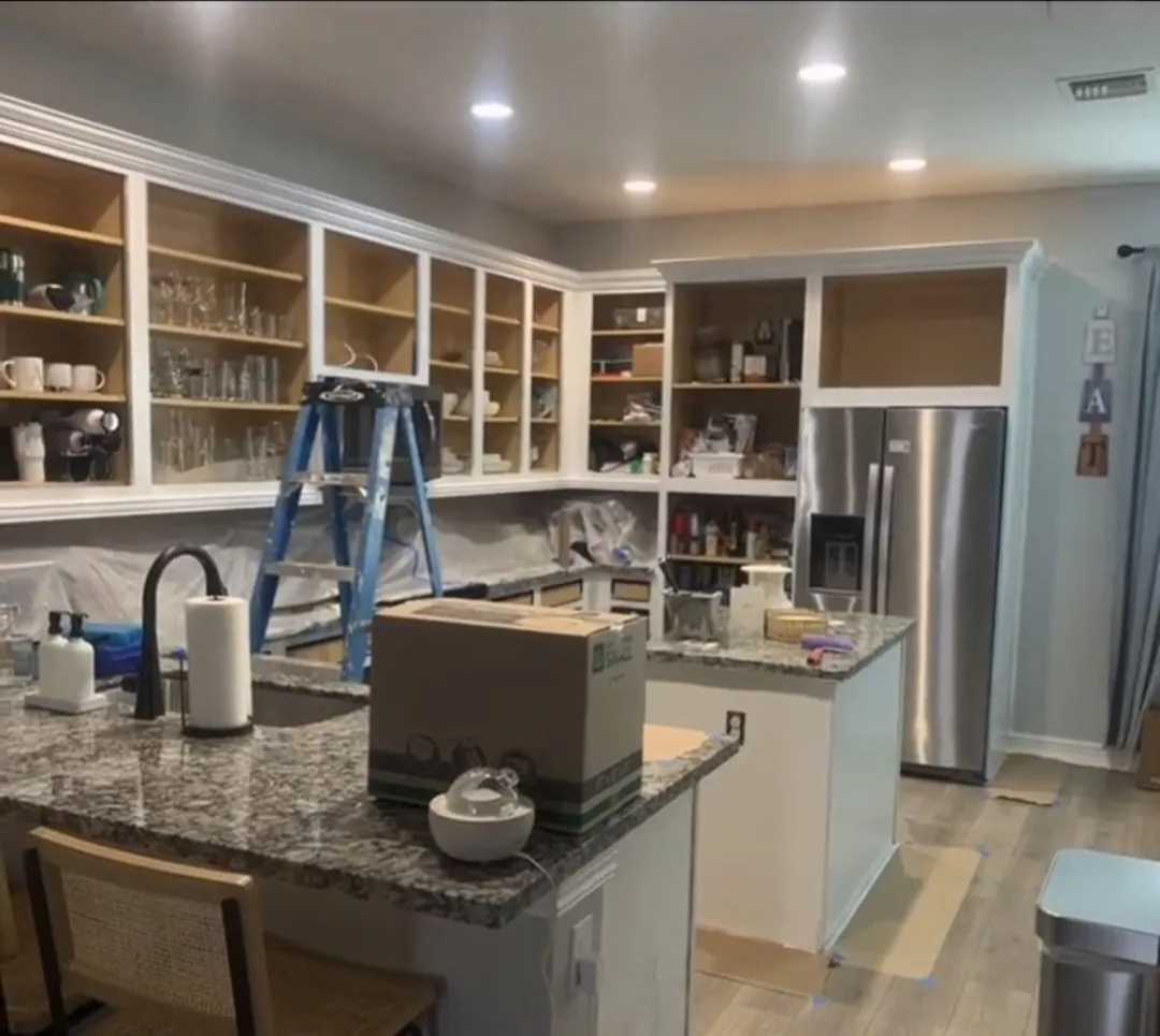 Shaker kitchen cabinets during painting — doors removed, plastic protection