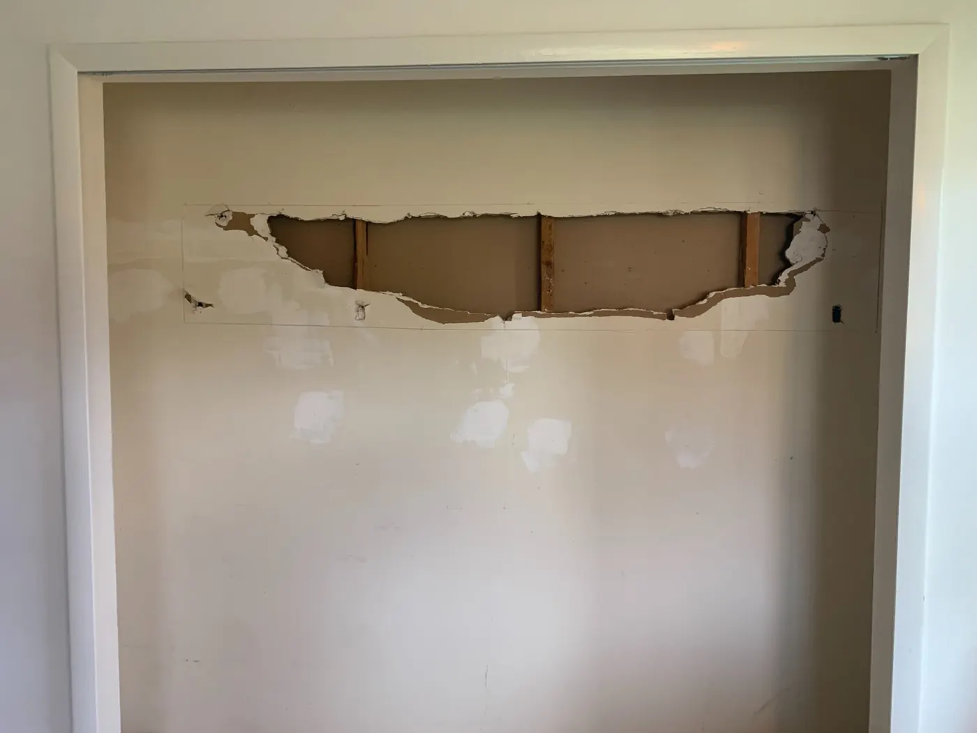 Damaged drywall opening exposing studs before repair