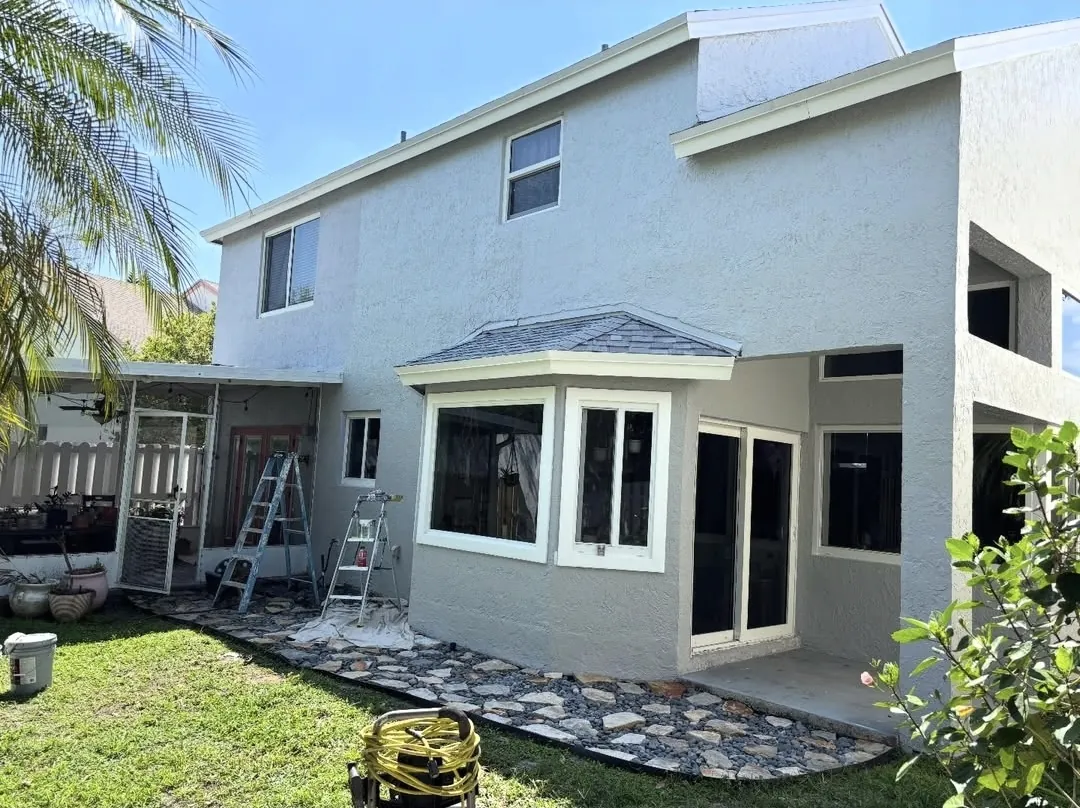 Rear of a home during exterior painting with ladders and drop cloths
