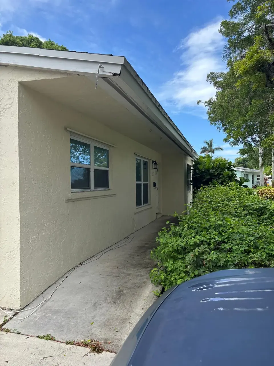 Side walkway of a cream stucco ranch home before painting