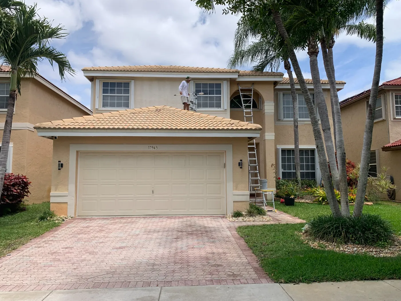 Painter on the roof rolling the second story of a two-story South Florida home