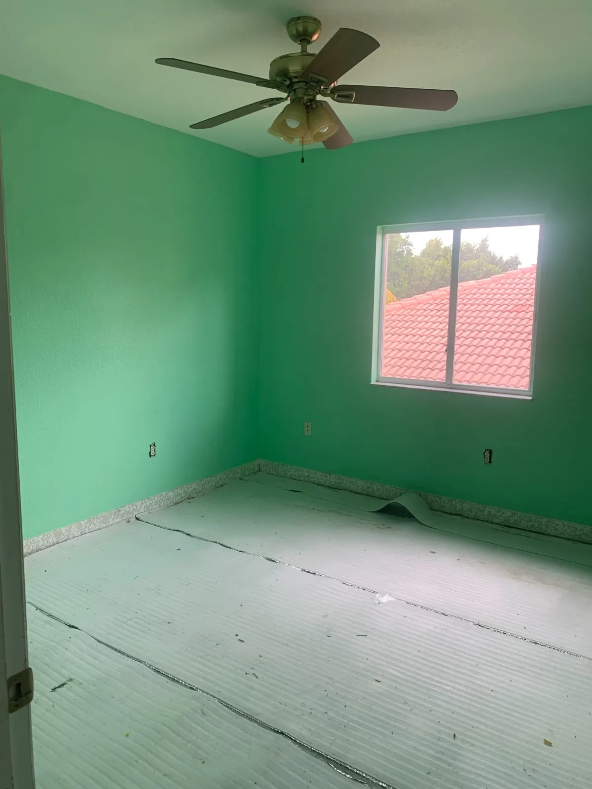 Bedroom with green walls and floor prep before repainting