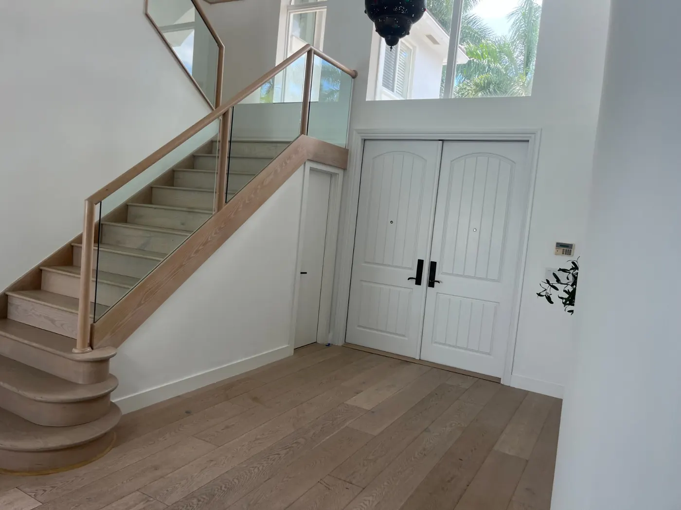 Finished white entry foyer with wood staircase and glass railing