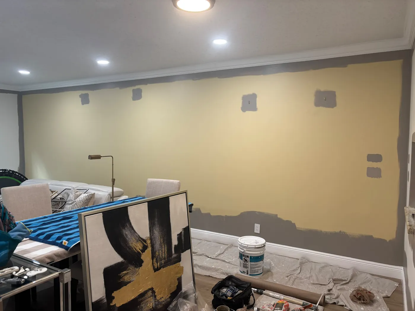 Living room mid-repaint with furniture covered and drop cloths down