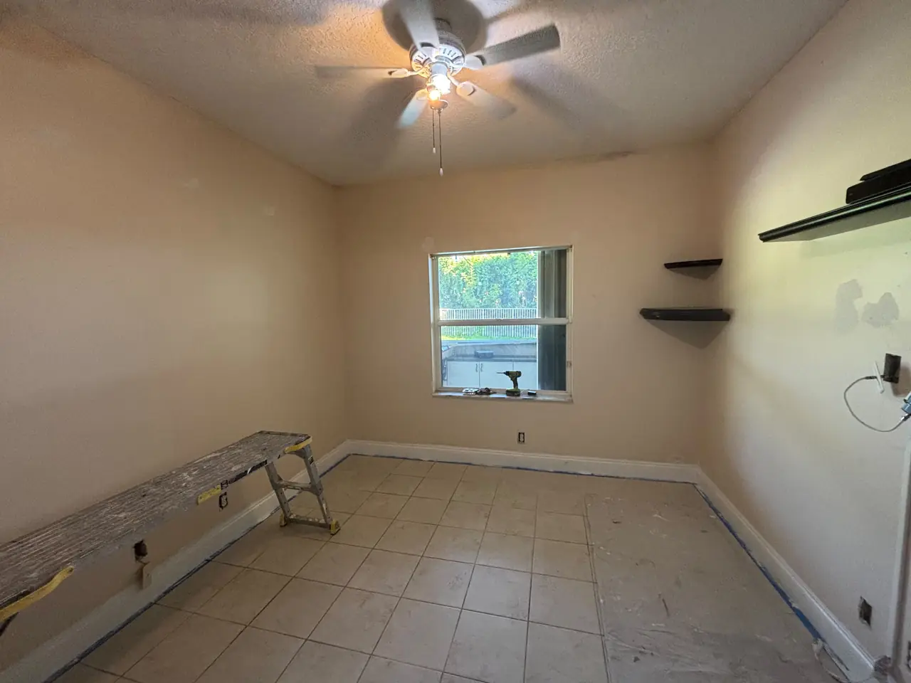 Interior room with baseboards taped and the floor covered before painting