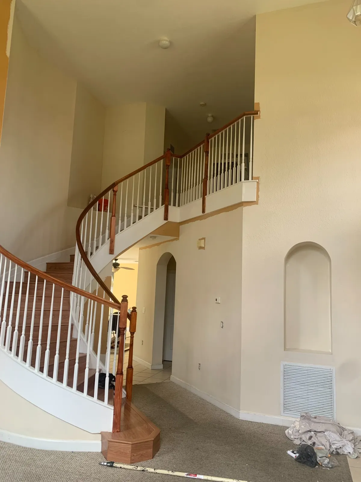 Curved staircase and foyer in beige before repainting